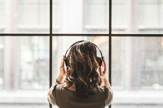 woman listening to music in front of window