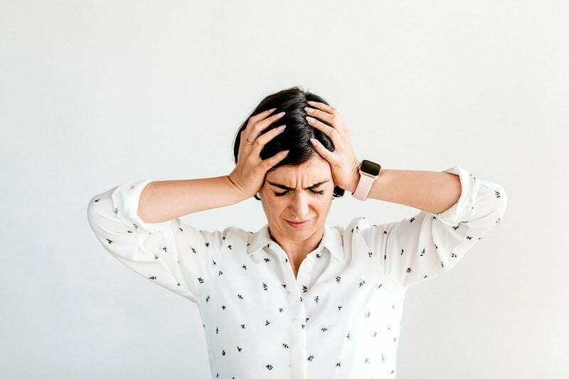 Woman grasping head with grimmace