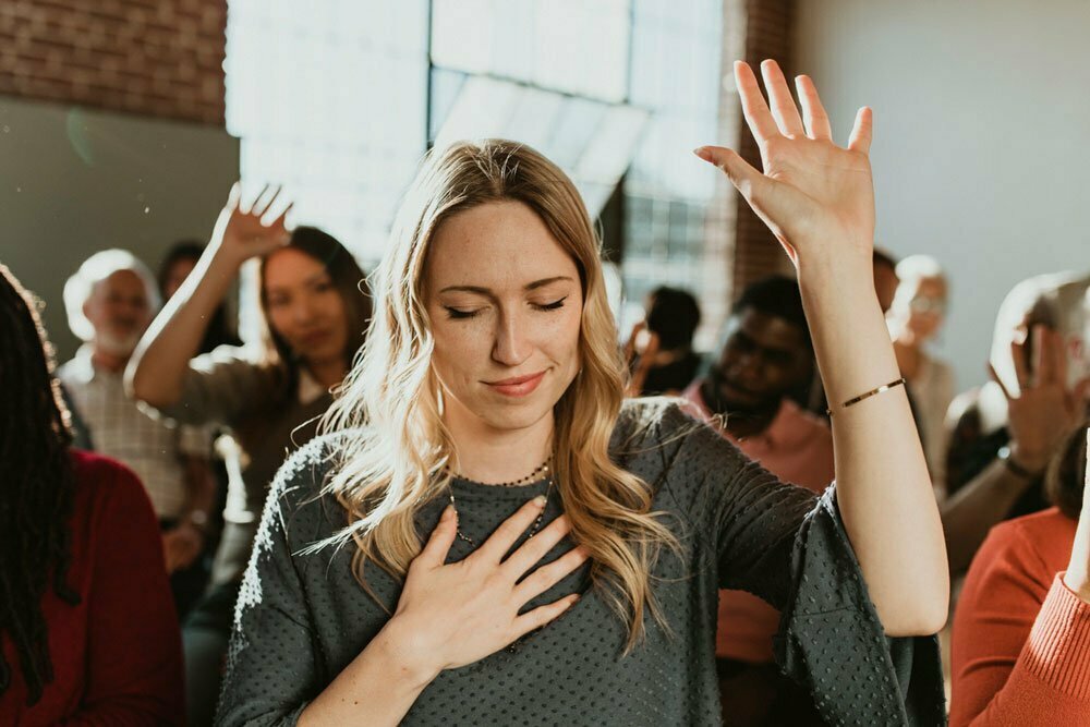 A woman holding her hand up and holding her heart