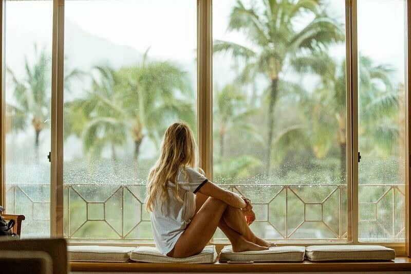 A woman in fetal position in front of a window in hawaii