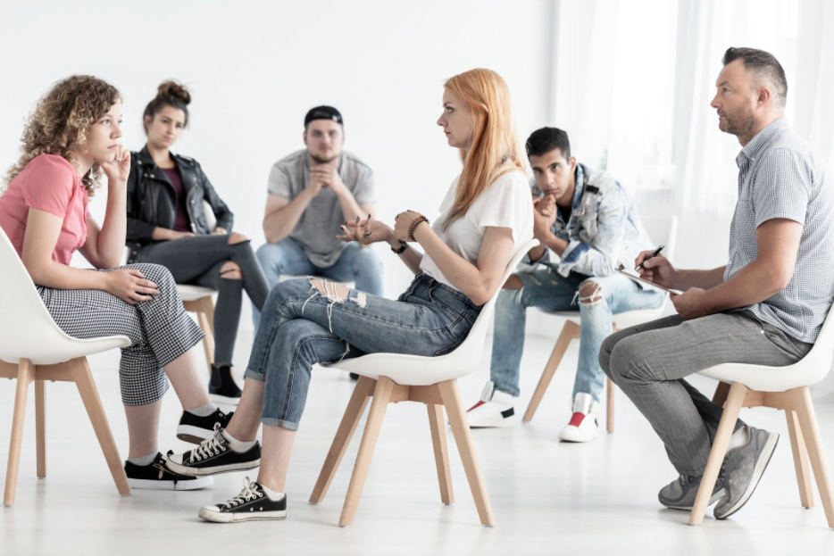 A group of people discussing addiction and therapy options