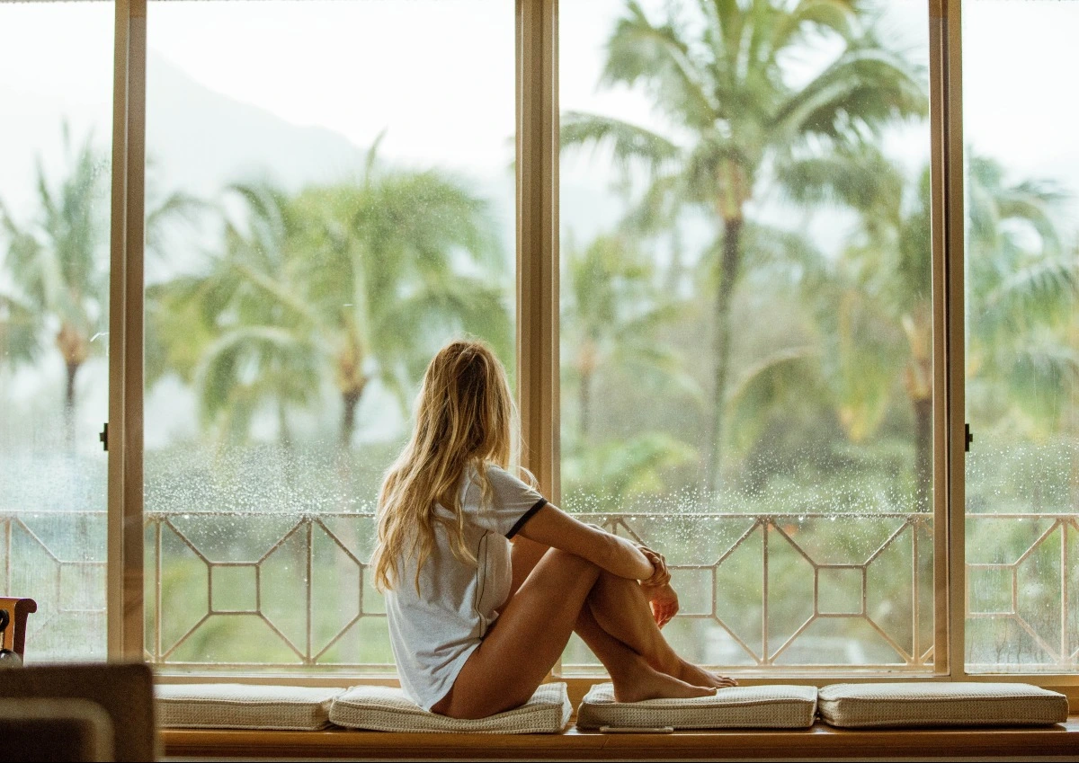 Girl holding knees at a window